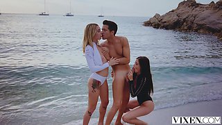 Blonde beauty Little Caprice and brunette Gabbie Carter share a massive cock on a sunny beach