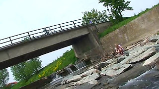 Blonde pissing outside in a river