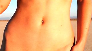 Curvy petite brunette strips at a beach