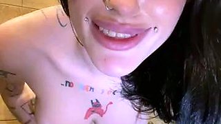 Inked vixen poses naked and masturbates in a public toilet